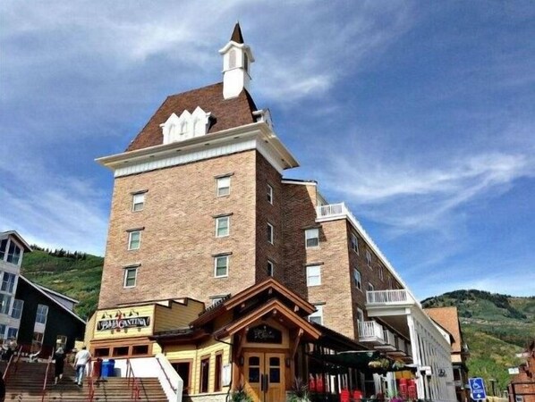 Stunning corner building with a prominent tower and brick facade, featuring evenly spaced windows and a wooden entrance.