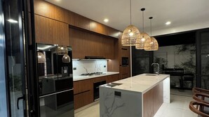 Una cocina moderna con armarios de madera, una isla central e iluminación colgante.