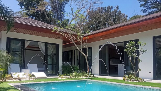 Una casa moderna con piscina, ventanas amplias y un jardín cuidado.