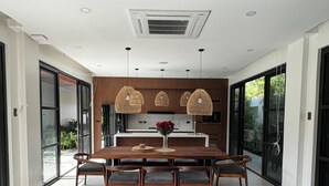Una sala moderna con un sofá gris, una mesa de comedor con sillas y un ventilador de techo.