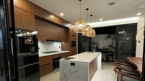 Una cocina moderna con armarios de madera, una isla de mármol e iluminación colgante.
