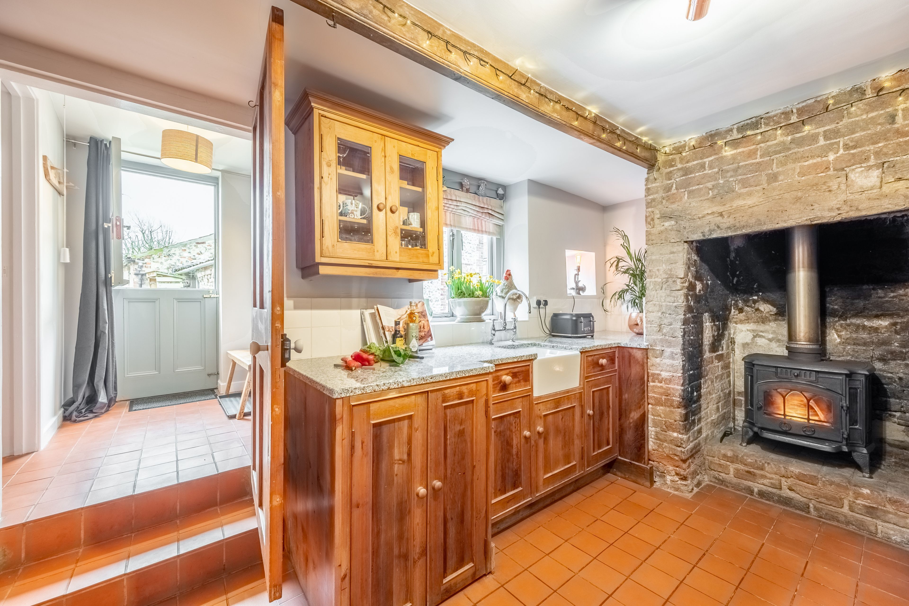 Une cuisine avec des meubles de rangement en bois, une cuisinière encastrée et une vue sur l’extérieur.
