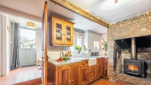 Une cuisine avec des meubles de rangement en bois, une cuisinière encastrée et une vue sur l’extérieur.