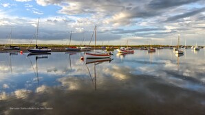 Un port de plaisance o ù sont amarrés plusieurs bateaux, l’eau est calme et le ciel est nuageux.