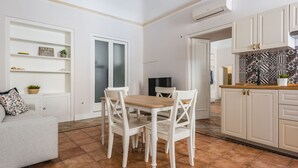 A compact kitchen with white cabinetry, a wooden dining table, and a sofa with decorative pillows. - Casa Core a Noto by Wonderful Italy (Noto)