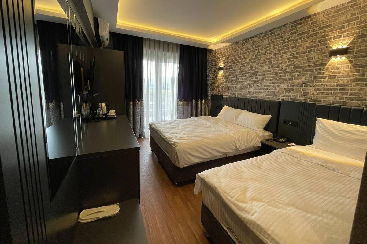 A hotel room with a large bed, a smaller bed, a desk, and a TV.