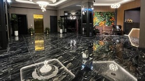 Un hall d ’entrée spacieux, doté d’un sol en marbre poli, de lustres modernes et d’un mur floral aux couleurs vives.