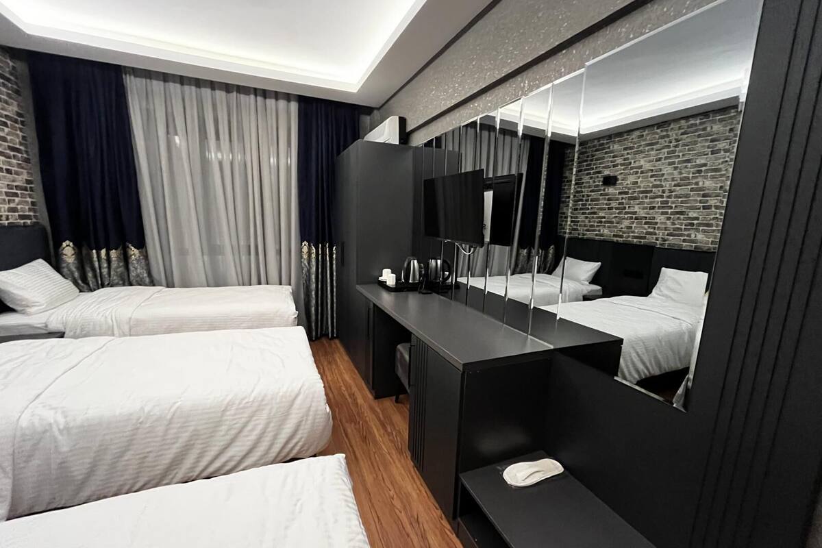 A modern hotel room with two beds, a large mirror, and a wooden floor.