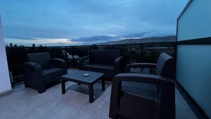 Un balcon doté de meubles en osier et d’une table, offrant une vue panoramique.