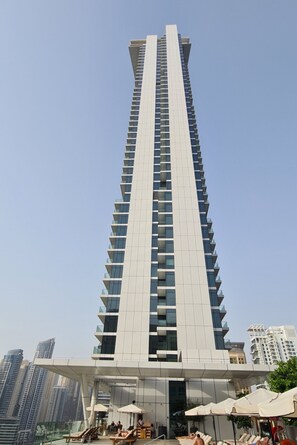 Un immeuble moderne et imposant, caractérisé par une conception verticale marquée, avec de nombreux balcons et une façade en verre.