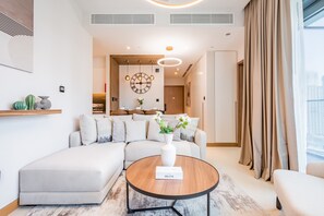 Un salon moderne avec un canapé d’angle, une table basse ronde et une horloge décorative au mur.