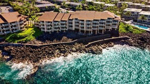 A coastal resort with multiple-story buildings, a rocky shoreline, and a clear view of the ocean.