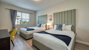 A hotel room with two beds, a desk, and a chair.