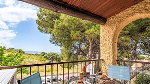 A balcony with a table set for two, a chair, and a view of the surrounding landscape. - Casa Maza Corta by Interhome (Lumio)