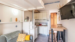 A compact living space with a sofa, a small kitchen area, and a TV mounted on the wall. - Casa Maza Corta by Interhome (Lumio)