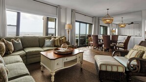 A spacious living room with a large sectional sofa, a coffee table, and a dining area with chairs and a table. - Prime Oceanfront Location: Pool, Balcony & Tennis Court (Wrightsville Beach)
