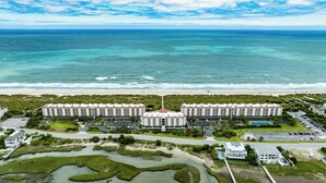 A large hotel with a central dome, multiple parking lots, and a view of the ocean. - Prime Oceanfront Location: Pool, Balcony & Tennis Court (Wrightsville Beach)