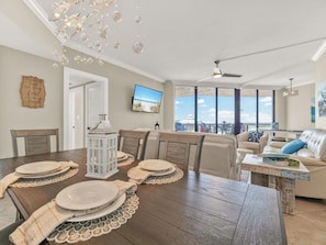 Un coin repas avec une table en bois dressée pour quatre personnes, une lanterne blanche et une vue sur la ville grâce à de grandes fenêtres.