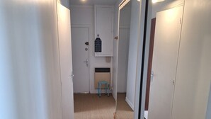 Kapea käytävä, jossa on matotettu lattia, valkoiset seinät ja peilillä varustettu kaapin ovi.
