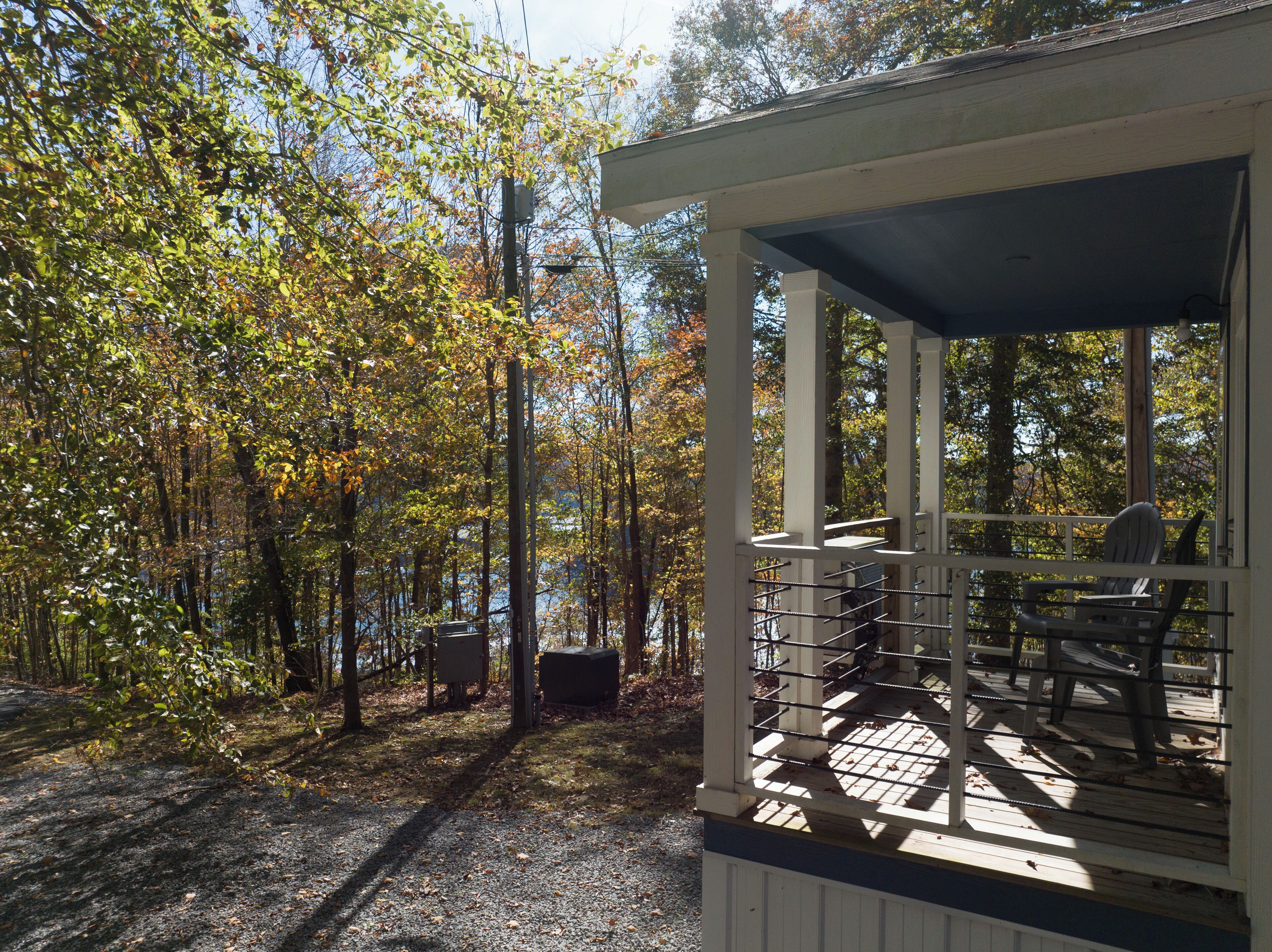 A covered outdoor deck with a view of a forested area and a body of water.