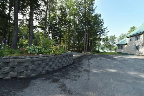 A two-story building with a green roof, surrounded by tall trees and a stone retaining wall. - Lakeside Luxury: Your Private Waterfront Escape (Lincoln)