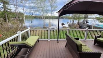 A deck with outdoor furniture, a view of a lake, and a covered area.