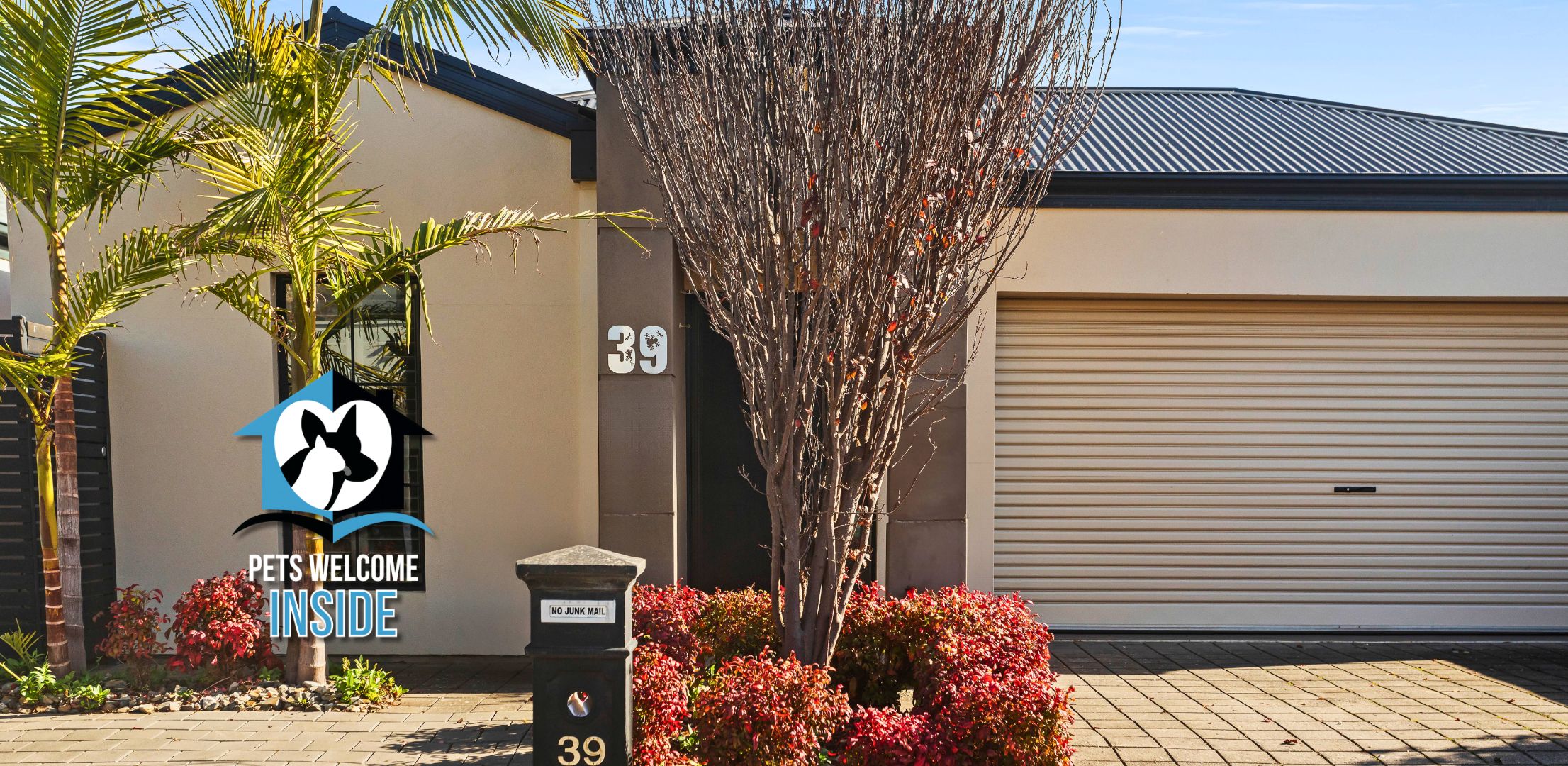 A building with a garage door, a sign reading 'Pets Welcome Inside,' and a mailbox with a 'No Junk Mail' sign.