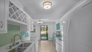 A modern kitchen with white cabinetry, a green tiled backsplash, stainless steel sinks, and a Samsung refrigerator. - Seascape Resort Villa -33B*Quiet Villa*Pools*Beachy (Miramar Beach)