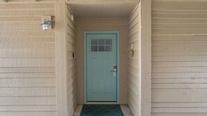 A narrow entrance with a teal door, a small step, and a green mat. - Seascape Resort Villa -33B*Quiet Villa*Pools*Beachy (Miramar Beach)