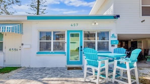 Un edificio con el número 457, una puerta y un patio con mesa y sillas.