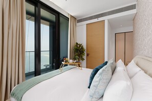 A modern hotel room with a large bed, a small table with a plant, and a view of the outdoors. - Luxury Living w/ Superb Sea Views in Address JBR (Dubai)