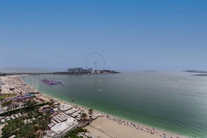 Een strand met een reuzenrad, helder water en strandparasols.