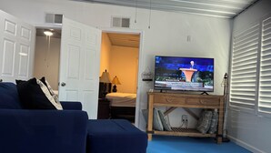 Ein Wohnzimmer mit Fernseher, einer Couch, einem Holzschrank und einem Deckenventilator.
