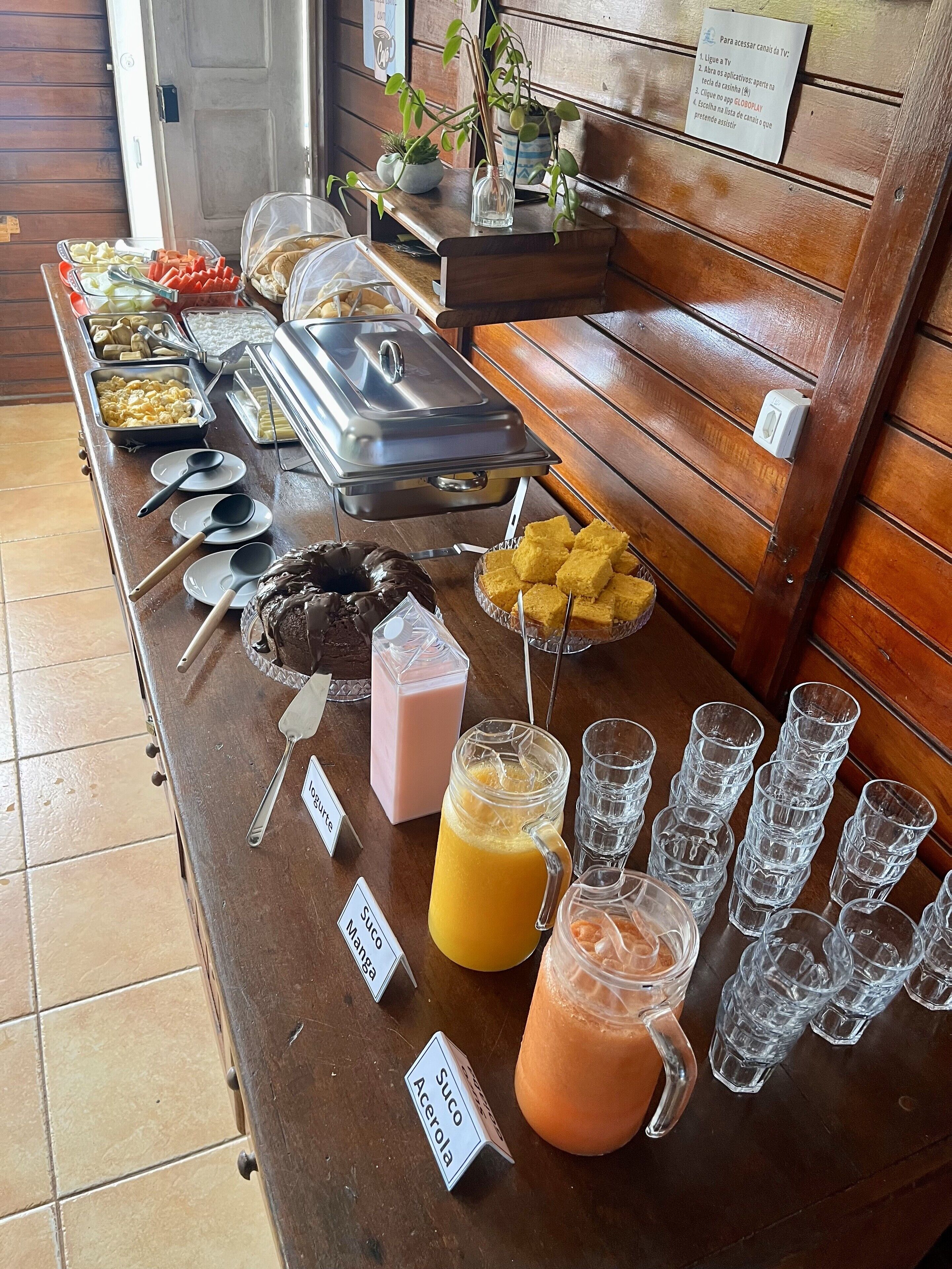 Un buffet con diverse portate e bevande, tra cui un'insalata di frutta, panini e un dolce al cioccolato.