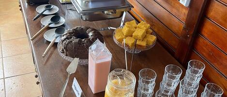 Un bufé con diferentes opciones de comida y bebidas, incluyendo una ensalada de frutas, sándwiches y un postre de chocolate.