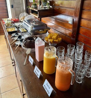 A buffet table with various food items and drinks, including yogurt, milk, and juices. - Pousada Suítes do Atlântico (Ilhéus)