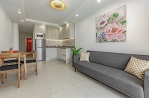 Une cuisine moderne avec un coin repas, un canapé gris et un grand tableau floral accroché au mur.