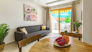 A modern living room with a grey sofa, wooden coffee table, and a painting of flowers. - Stunning apartment in Costa Adeje with heated pool. (Costa Adeje)