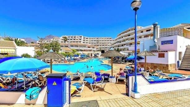 A hotel pool area with sun loungers, umbrellas, and a clear blue sky. - Stunning apartment in Costa Adeje with heated pool. (Costa Adeje)