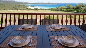 A table set for two with a view of a beach and mountains. - Harenae Beach Gataway by Wonderful Italy (Olbia)