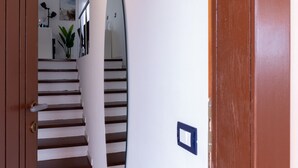 A hallway with a wooden door, a white wall, and a mirror. - Harenae Beach Gataway by Wonderful Italy (Olbia)