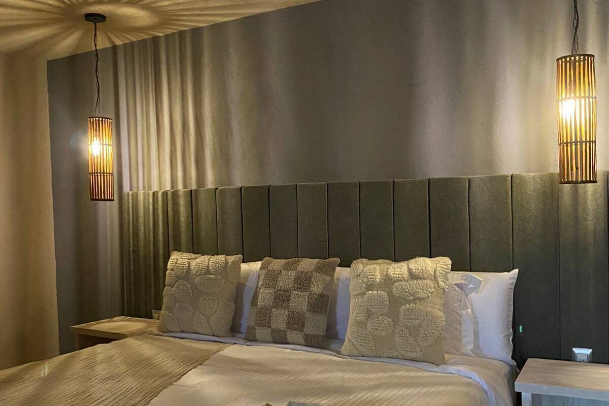 A large bed with a wooden headboard, two bedside tables, and two wall-mounted lamps.