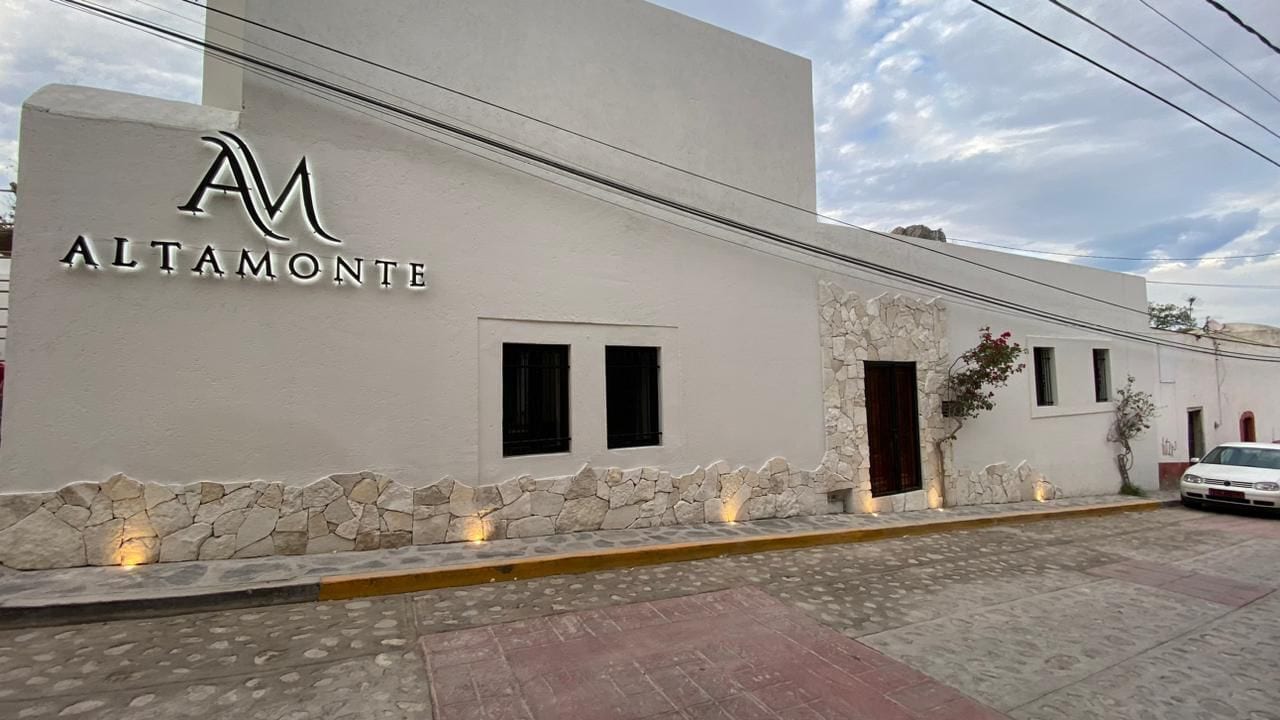 A building with a white facade, a stone base, and a logo with the letters 'AM'.