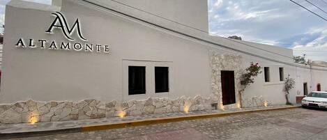 A building with a white facade, a stone base, and a logo with the letters 'AM'.