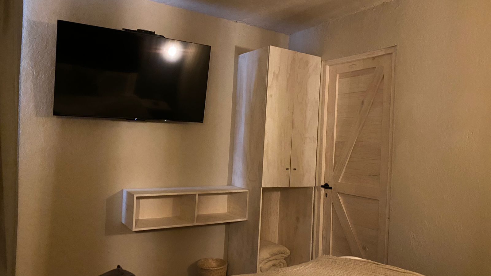 A room with a mounted TV, a wooden cabinet, and a door.