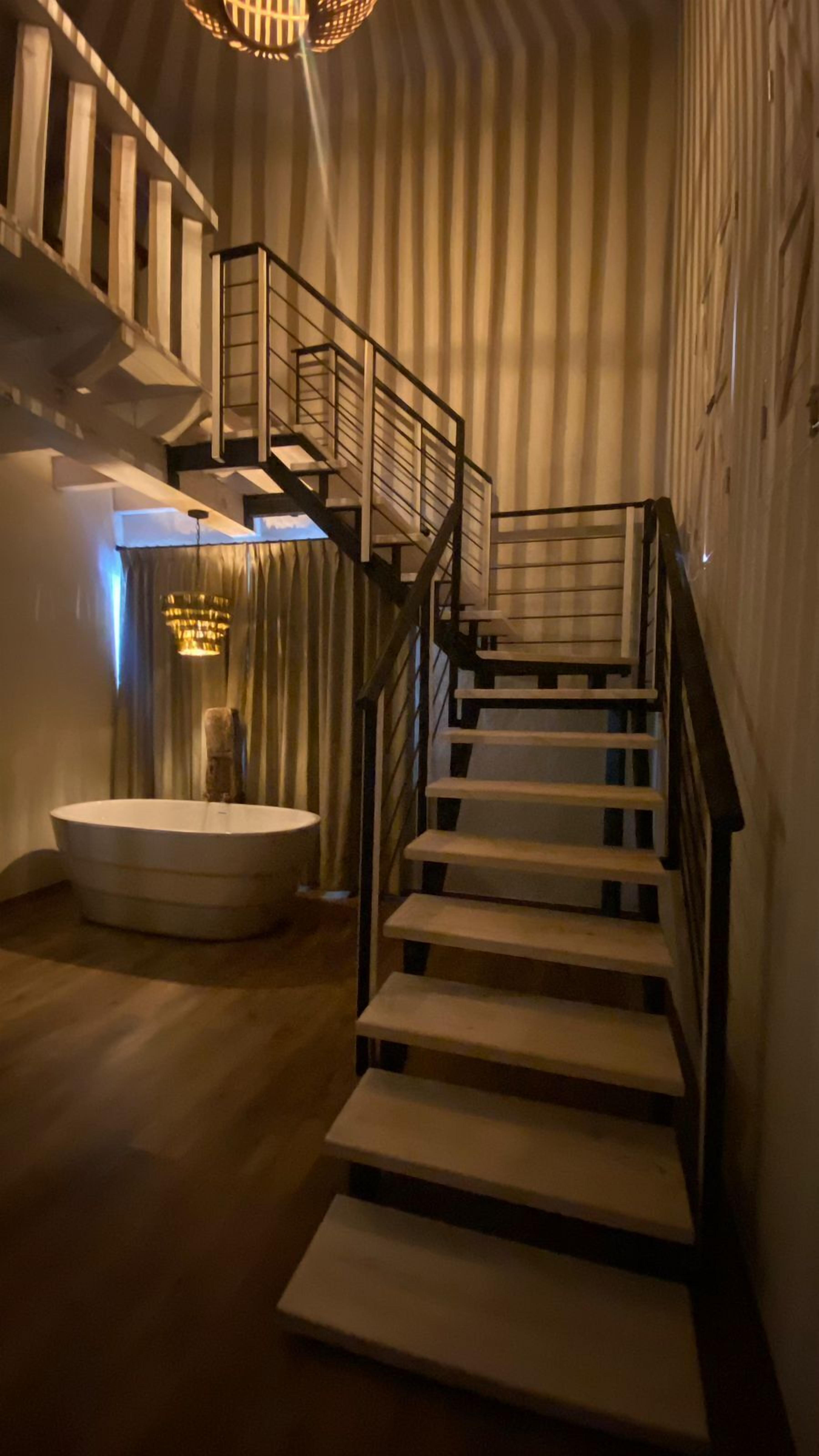 Un escalier avec des marches en bois et des rampes en métal, menant à un niveau supérieur.