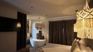 A modern bedroom with a large bed, a built-in bathtub, and a hanging light fixture. - ALTAMONTE HOTEL BOUTIQUE (Ezequiel Montes)