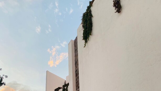A courtyard with white walls, arches, and potted plants. - ALTAMONTE HOTEL BOUTIQUE (Ezequiel Montes)
