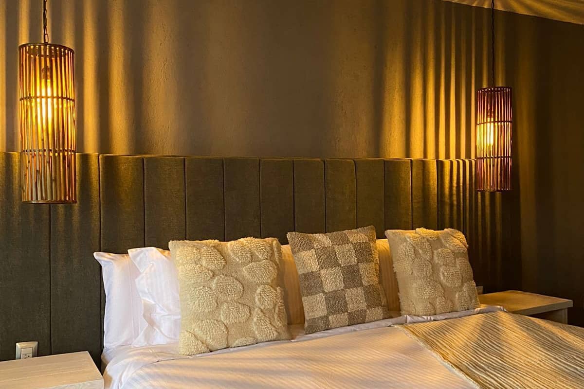 A neatly made bed with two pillows, a bedside table, and two wall-mounted lamps.