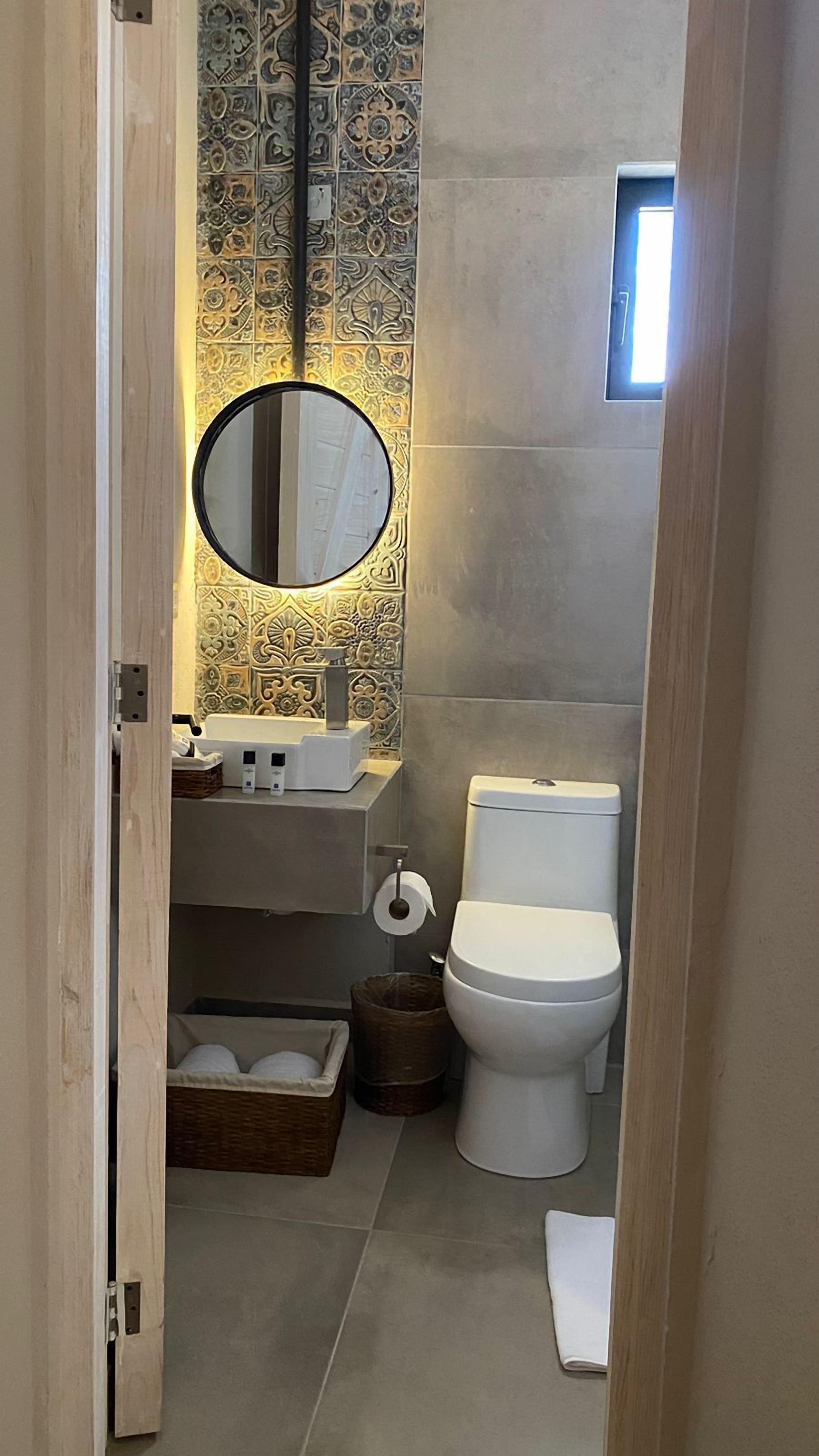 A compact bathroom with a modern design, featuring a sink, toilet, and decorative tiles.